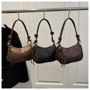Close-up of three leather crescent shoulder bags in brown and black with knotted straps
