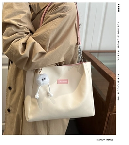 Détail du sac cabas beige avec bandoulières roses et un porte-clé pompon en peluche