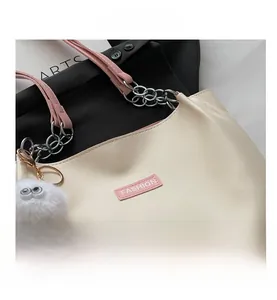 Détail du cabas beige avec bandoulières roses, chaîne argentée et breloque tendance