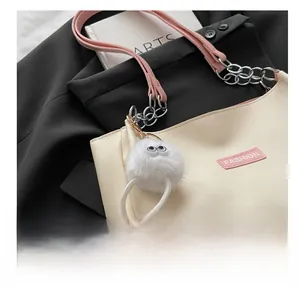 Gros plan d'un charme en peluche blanche à longues jambes sur un sac cabas en cuir beige