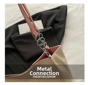 Détail de la chaîne argentée reliant le sac en cuir beige et la bandoulière rose