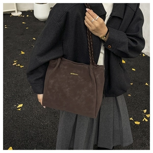 Detail einer dunkelbraunen Shopper-Tasche aus Mattleder mit geflochtenem Schultergurt