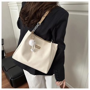 Chic beige tote bag detail featuring fluffy bunny ear charm and metallic chain strap