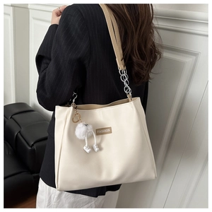 Detail of cream PU leather bucket bag with silver chain strap and plush ball pendant
