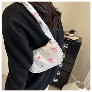 Detailed view of the white floral tote bag with pink bows worn over the shoulder