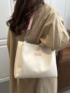 Large cream tote bag with pink straps and fashion label shown on model's shoulder