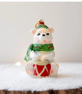 Close-up of a resin Christmas polar bear figurine with glitter details playing a red drum
