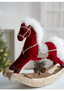 Close-up of red velvet rocking horse Christmas ornament with gold base and glitter details