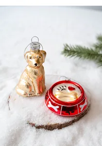 Detailed view of handcrafted golden glass dog and red bowl Christmas ornaments on snow