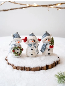 Close-up of three resin snowmen with realistic knit textures and festive accessories
