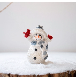 Close-up of resin snowman ornament with knit texture, blue scarf and red bird detail
