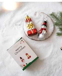 Detail of Christmas glass ornaments including snowman and gift box in festive gift packaging