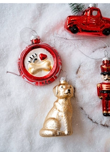 Close-up of glass Christmas ornaments featuring dog and soldier on snowy background