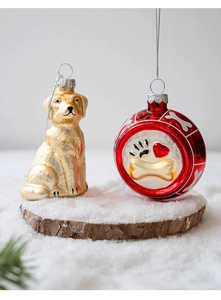 Detailed view of glass dog and heart bone ornaments on a snowy wood base for Christmas