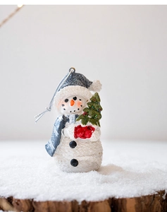 Detail of Christmas snowman figurine with knitted texture and mini tree on snow