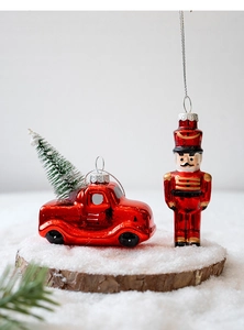 Detail of red vintage truck and nutcracker glass ornaments on snowy wooden base