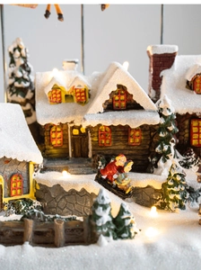 Close-up of lighted Christmas village house with LED lights and miniature skiers