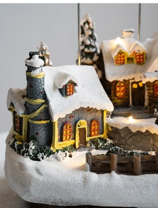 Detailed macro of a light-up Christmas snow village house with warm glowing LED windows