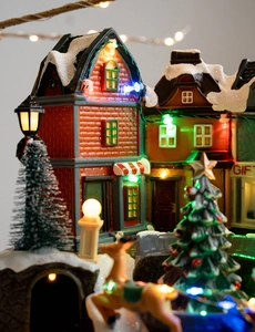 Macro shot of a glowing Christmas village miniature with reindeer and colorful LED trees