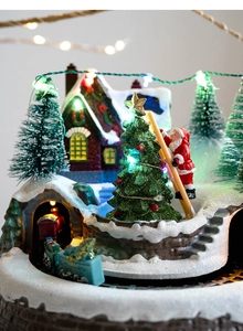 Macro view of Christmas village with glowing tree, Santa figure and rotating train