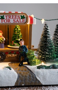 Macro detail of lighted TREES FOR SALE stall with miniature figurine in snowy scene