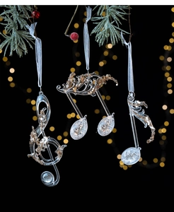 Close-up of musical note Christmas ornaments with champagne gold sequins on pine branches