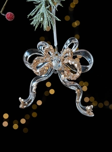 Close-up of a Christmas bow ornament with gold sequins and gem on snowy pine branch