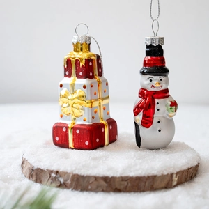 Christmas glass ornaments set with a snowman and stacked gift boxes on a snowy wood base
