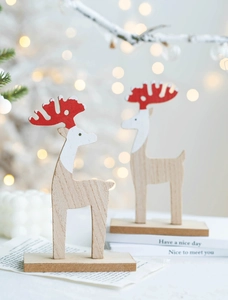 Detail of wooden reindeer ornaments with red antlers and snowy accents on a warm wood base