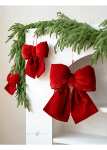 Detailed view of red velvet Christmas bows in three sizes hanging on a white fireplace mantle