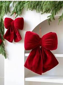 Close-up of red velvet Christmas bows with hanging strings on green pine branches