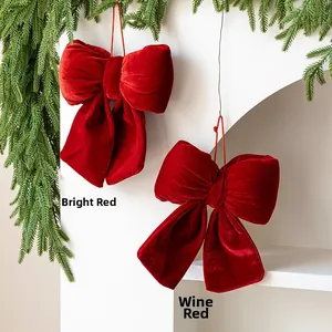 Detail of red and wine red velvet bows hanging on green pine branches for Christmas decor