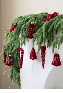 Close-up of red flocked Christmas ornaments with silver glitter hanging on pine branches