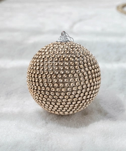 Close-up of champagne foam Christmas ball with sparkling gold rhinestones and silver hook cap