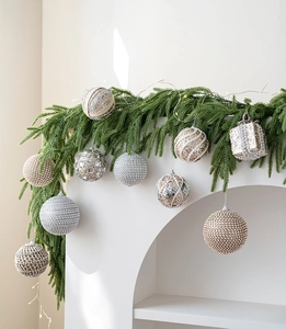 Detailed view of champagne foam Christmas ornaments with sequins hanging on pine needles