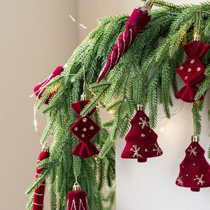 Set of burgundy velvet Christmas ornaments with silver sequins on green pine needles