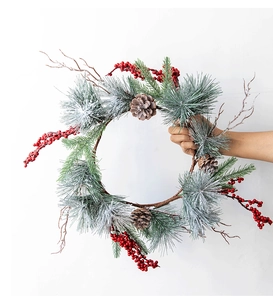 Detail of Christmas wreath with frosted pine needles, red berries and natural pine cones