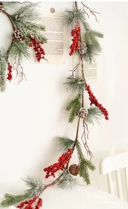Detail of Christmas garland with snow-frosted pine needles, red berries, and natural pinecones