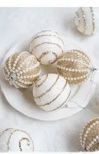 Dettaglio di palline di Natale color champagne con perle e glitter in piatto bianco