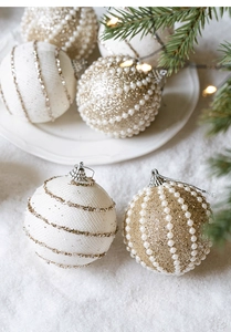 Dettaglio di palline di Natale champagne con glitter dorati e perle su rami innevati