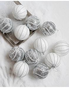 Dettaglio di palline di Natale champagne da 8cm con perle e paillettes su neve bianca