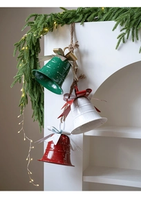 Three metal Christmas bells with polka dots, bows and hemp rope hanging on pine branches