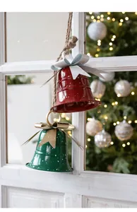 Macro shot of red and green Christmas iron bells with festive bows on a rustic window