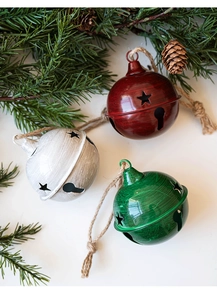 Close-up of three 8cm metal Christmas bells with star cutouts and rustic hemp rope