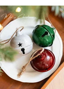 Close-up of red and green metal Christmas bells with star cutouts on a white plate