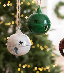 Detail of vintage metal Christmas bells with star cutouts on a rustic jute rope