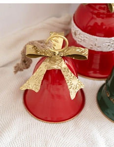 Close-up of red metal Christmas bell with golden bow and rustic hemp rope hanger