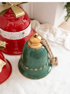 Close-up of green and red metal Christmas bells with golden bow and rustic rope detail