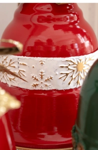 Macro detail of red Christmas bell ornament with embossed golden snowflakes on white band