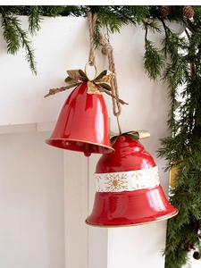 Detail of red metal Christmas bells with gold snowflakes and rustic twine hanger